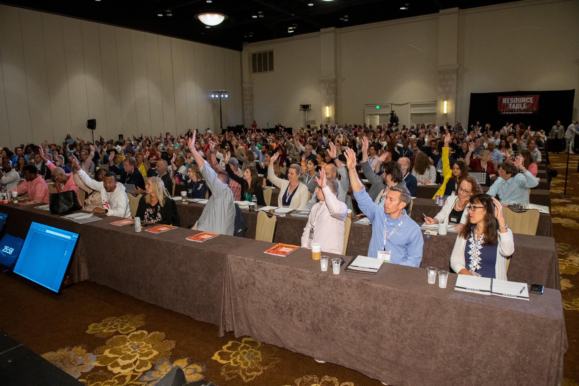 Law firm owners raising their hands in a large HTM conference room